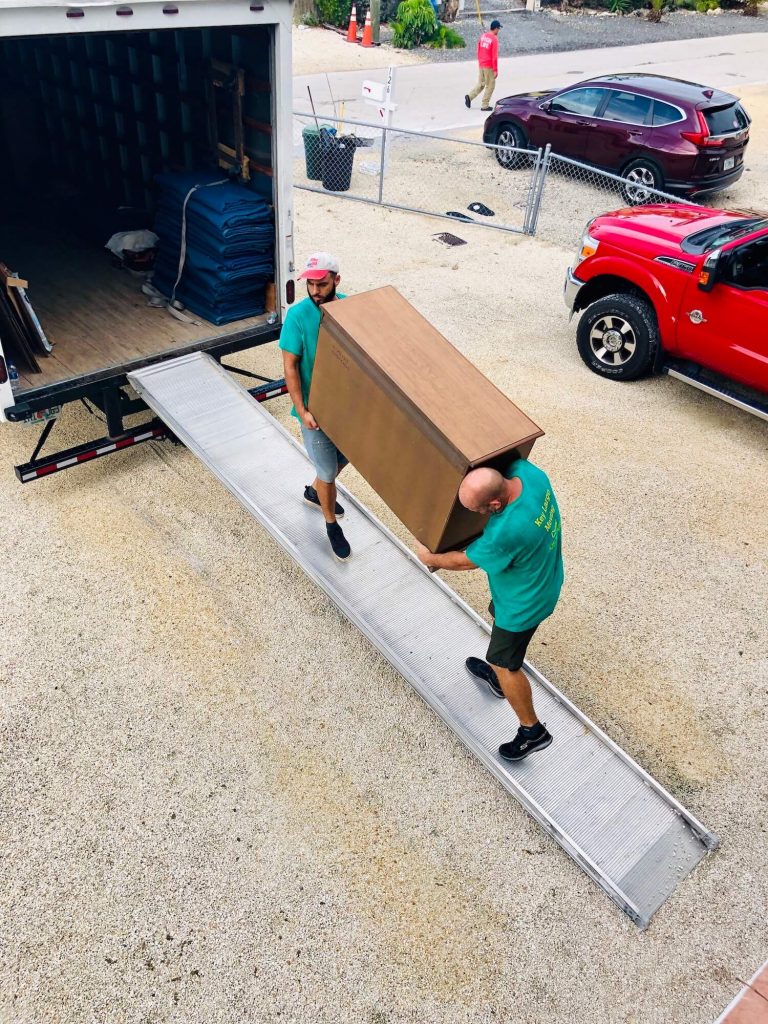 Two men lifting a piece of furniture on a ramp to get it on truck